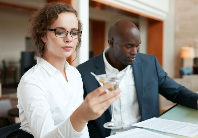 Businesswoman having a cocktail with a business man sitting by at bar counter