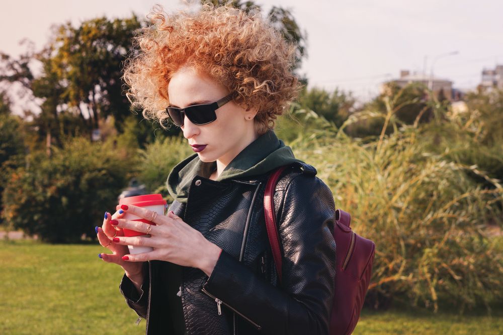 Curly haired woman with coffee outdoors