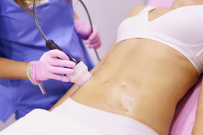 Professional in scrubs performing cosmetic procedure on torso