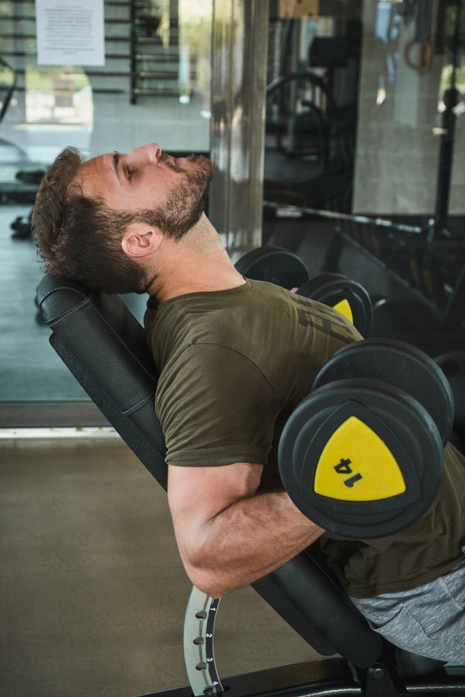 Strong man exercising with dumbbells in gym