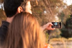 Couple kissing and taking photo outdoors