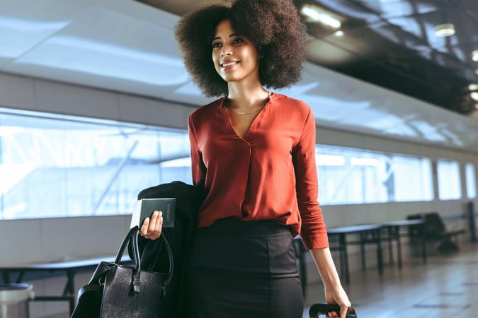 Smiling businesswoman with luggage walking at airport