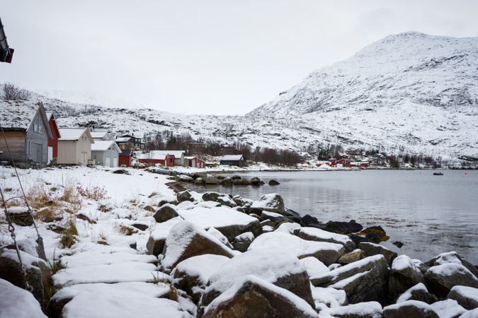 Tranquil lake against snowy hills in cold overcast weather