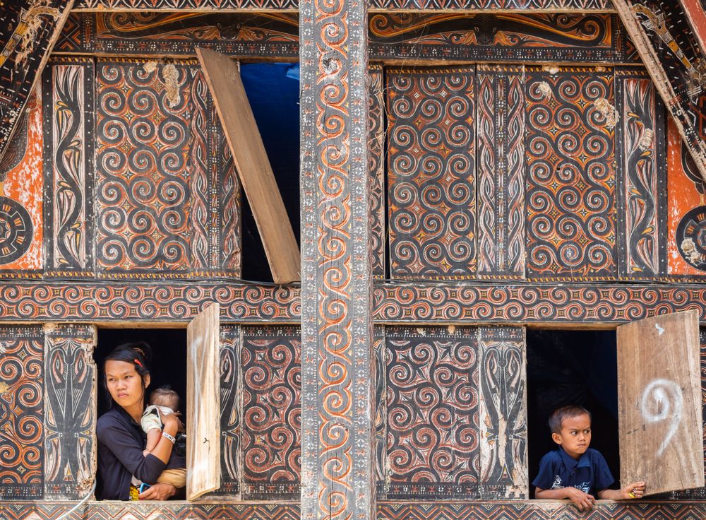 Bali, Indonesia - August, 15 2015: Mother with baby and kid looking out windows