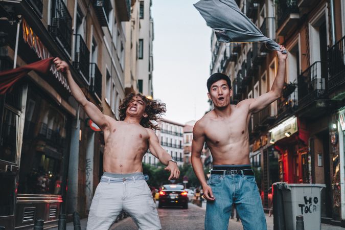 Rebellious shirtless multiracial men shouting while standing together on city street