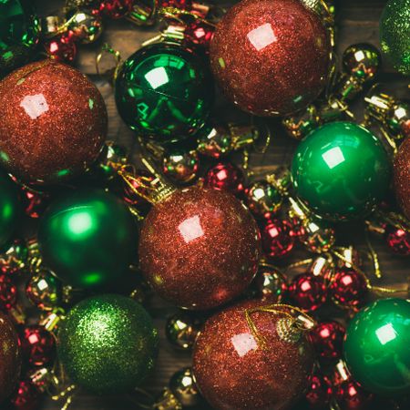 Close up of tree ornaments, large and small red, green and gold baubles, square crop