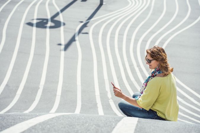 Modern relaxed woman on marked road and browsing smartphone