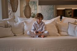 Cheerful boy using smartphone on sofa