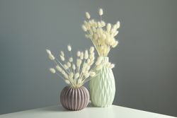 Textured round vase and tall vase filled on table with dried grass in grey room