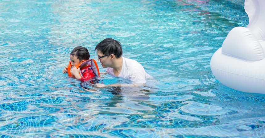 Father helping son swim in lifejacket