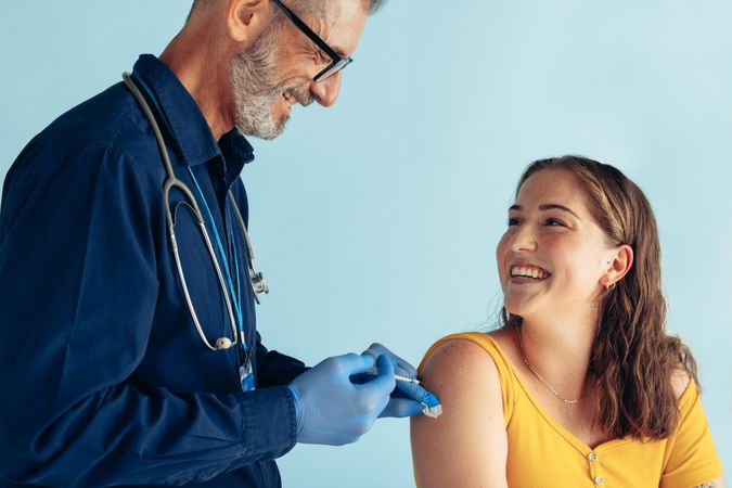 Smiling woman looking at doctor while receiving vaccine