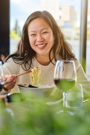 Young female eating ramen in restaurant