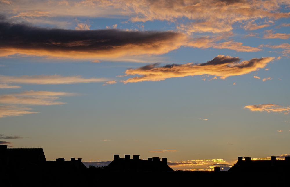 Blue sky with colorful clouds over roofs