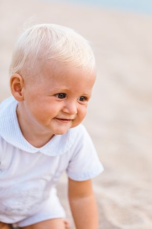 Portrait of a blonde baby smiling on the beach