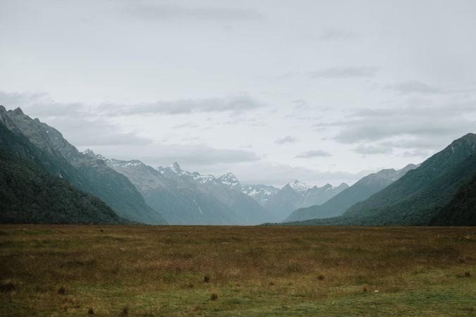 Valley with yellow grass and rocky mountains with snow
