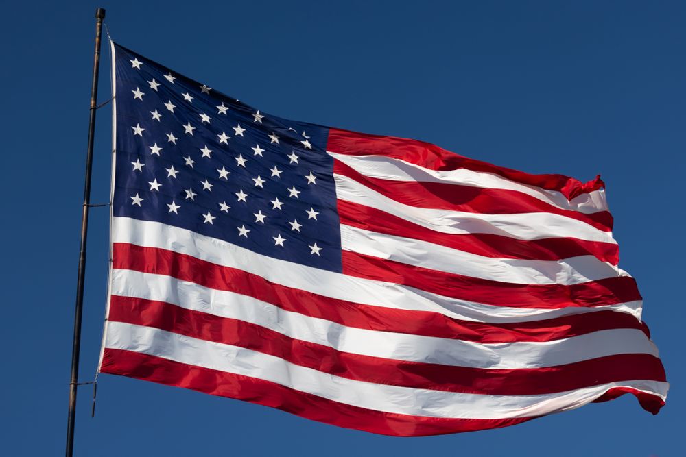 American Flag Waving In Wind Against a Deep Blue Sky.