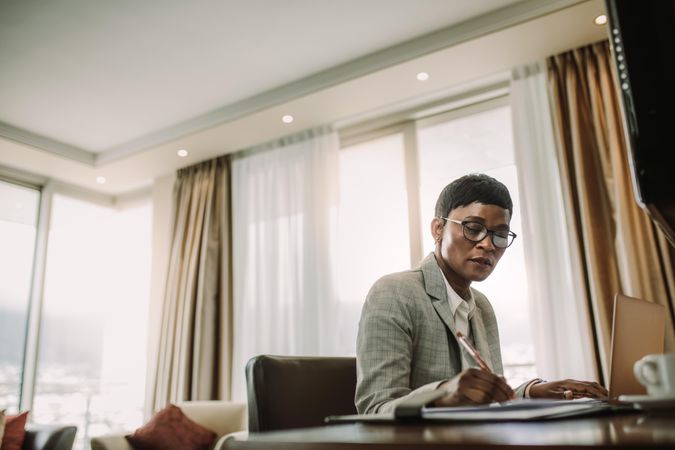 Businesswoman sitting at hotel room desk and working
