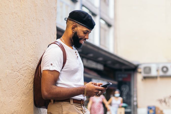 Stylish Black man using smartphone outdoors in the city