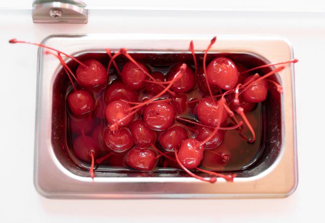 Close up photo of a metal tray filled with cherry toppings on an ice cream parlor counter