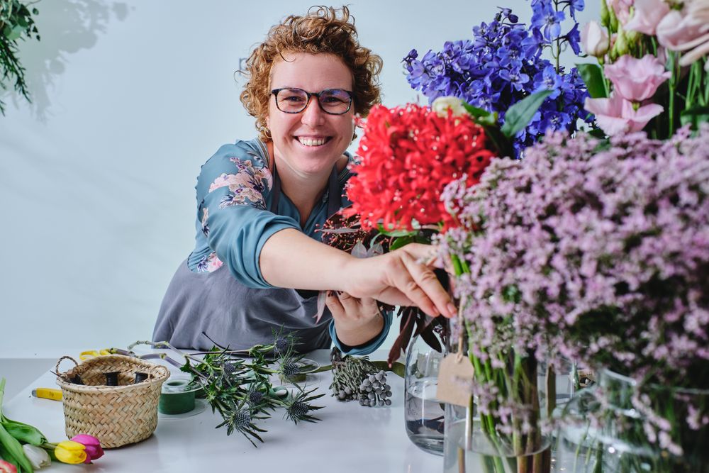 Smiling woman with blooming flowers in floral store