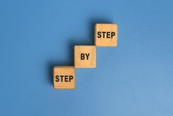 step by step word on wooden blocks staircase isolated on blue background. concept of success progress or career