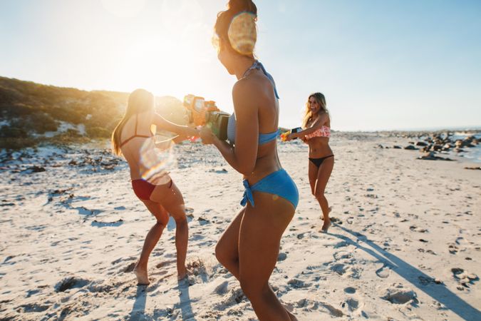 Fit group of women playing with squirt guns at the beach