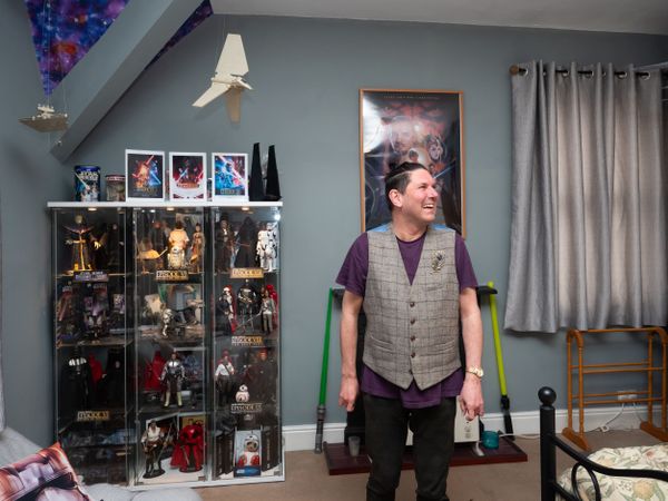 Man smiling at home in front of figuring collection