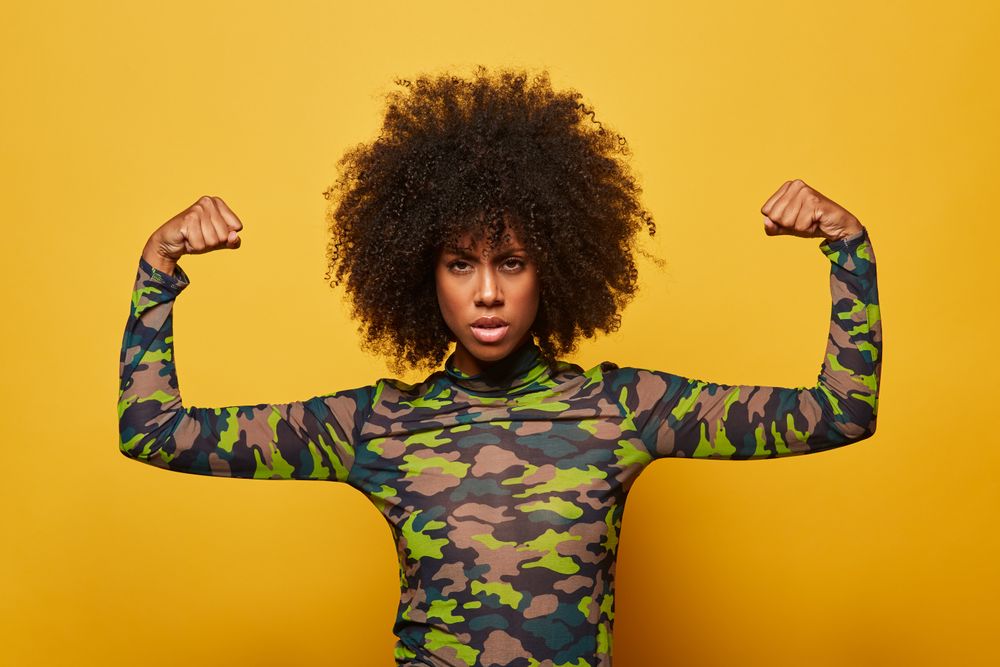 Powerful woman in military clothes flexing biceps