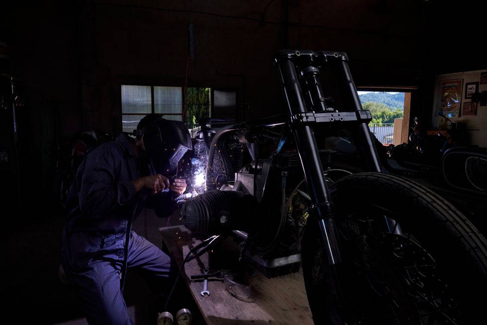 Unrecognizable mechanic repairing motorbike in garage