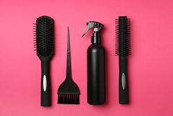 Flat lay with hairdresser accessories on pink background, top view