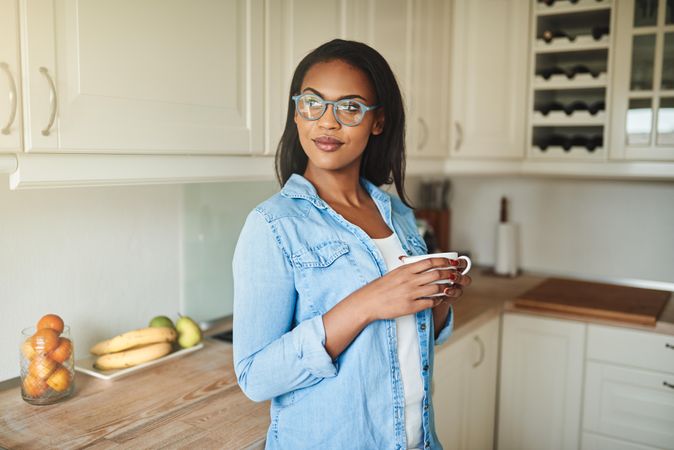 Woman reflecting in her kitchen holding a cup of tea