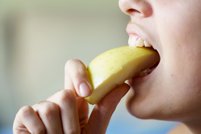 Side view of girl eating slice of apple