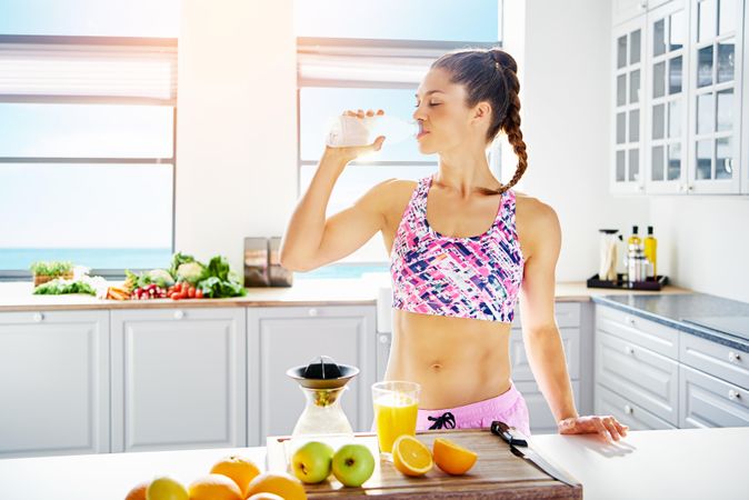 Athletic woman sipping water in bright kitchen