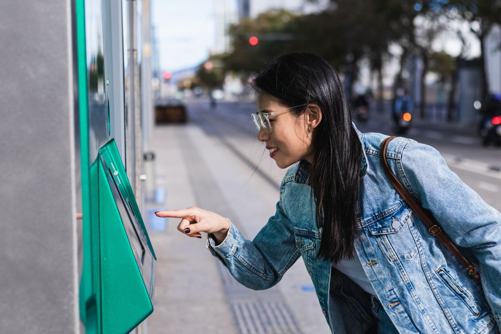Long-haired brunette Chinese woman pulling out a train ticket at the station