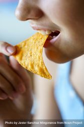 Close up of anonymous teenage girl eating crunchy Mexican tortilla chip bE9R1l