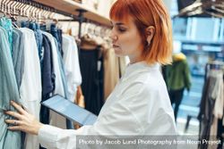 Businesswoman working in clothing store taking stock of clothes 5RjXW5