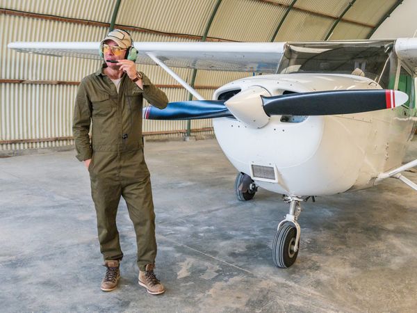 Confident pilot beside retro plane in hangar