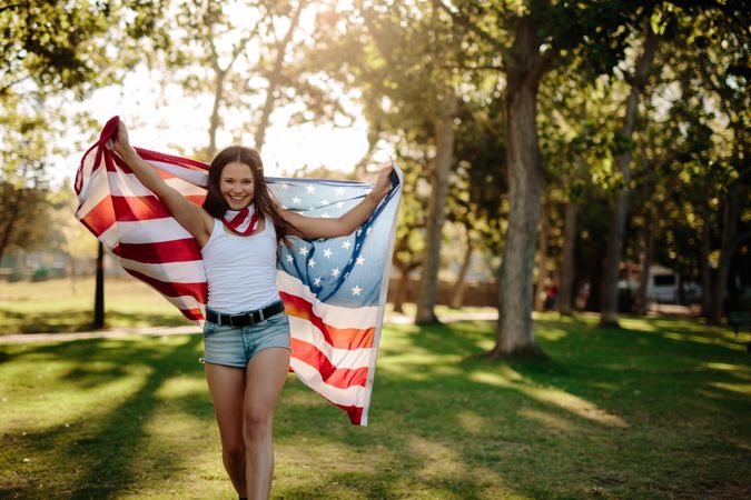 Smiling woman with American flag at park