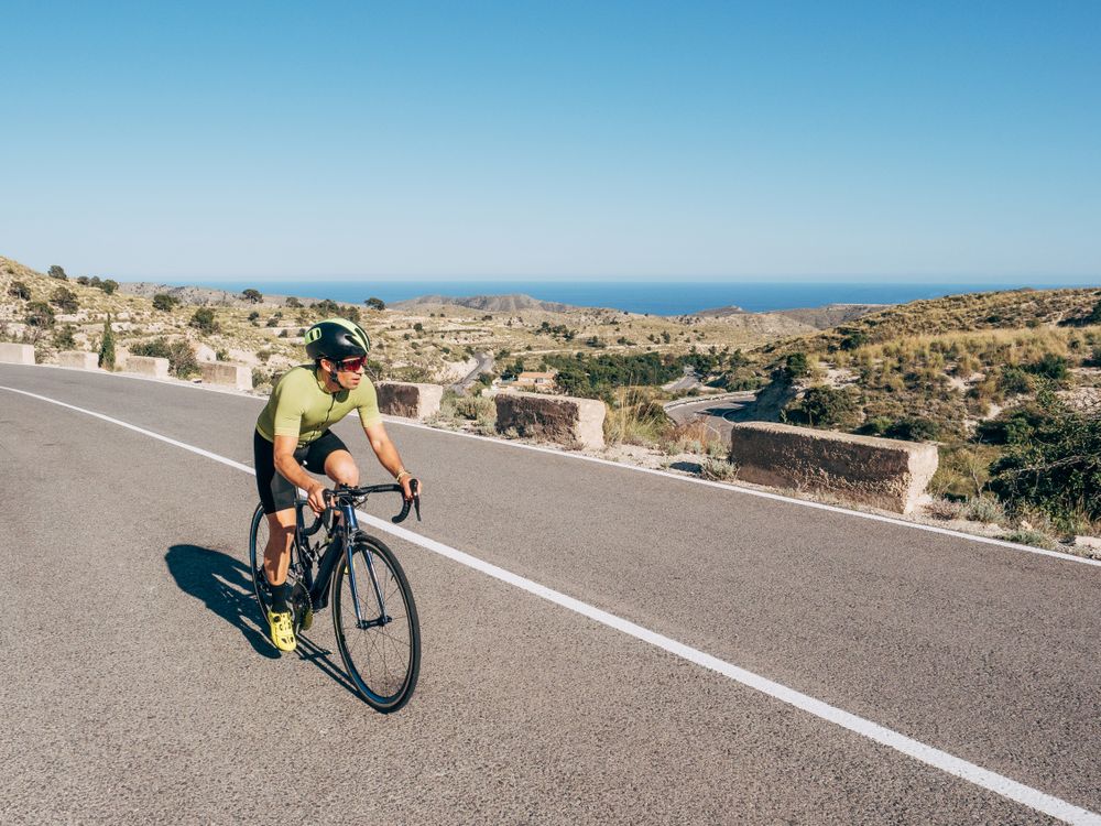 healthy man riding a bicycle on a mountain road in a sunny day