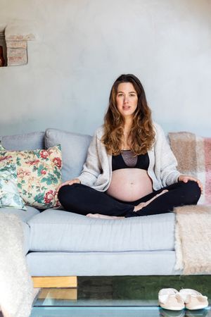 Pregnant woman sitting cross legged lounging at home