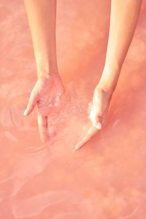 Female holding healing salt pile in pink water