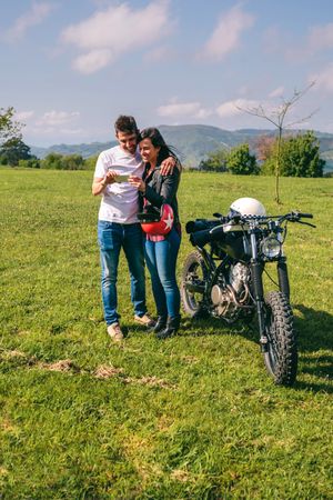 Couple looking mobile with a motorcycle