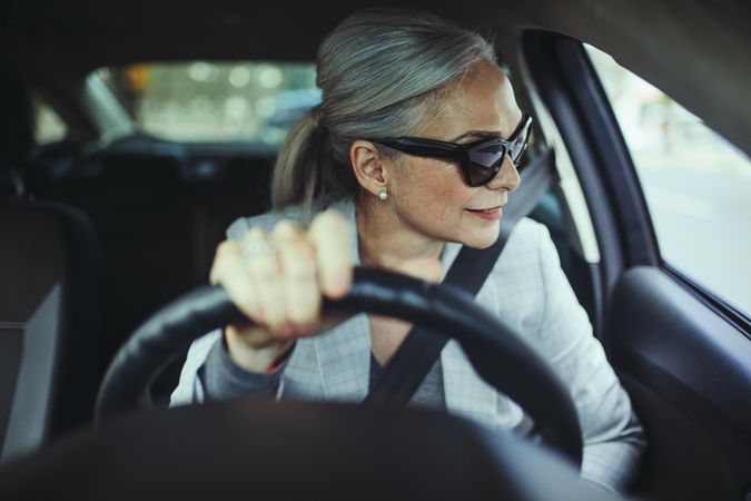 Beautiful older woman looking away while driving car