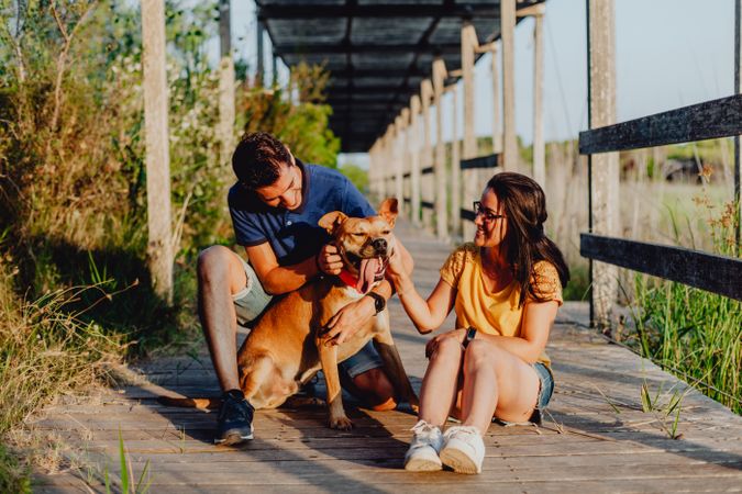 Happy adult couple having fun with dog at countryside