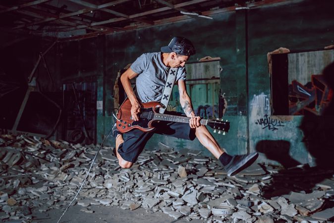 Musician playing electric guitar in abandoned place