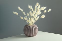 Round and ridged vase in grey room filled with dried flowers