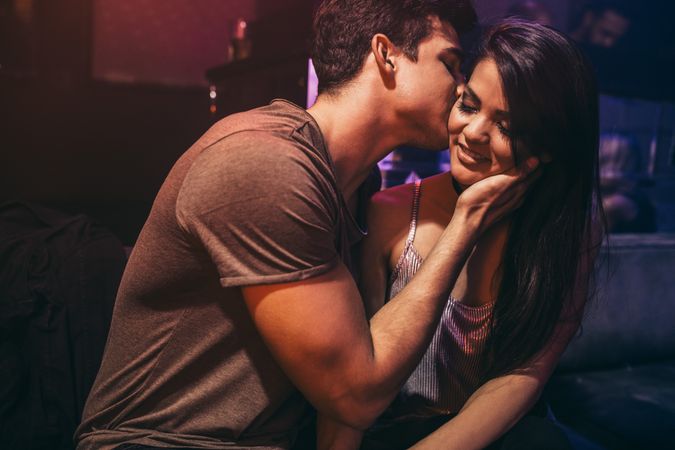Man kissing girlfriend sitting at lounge bar