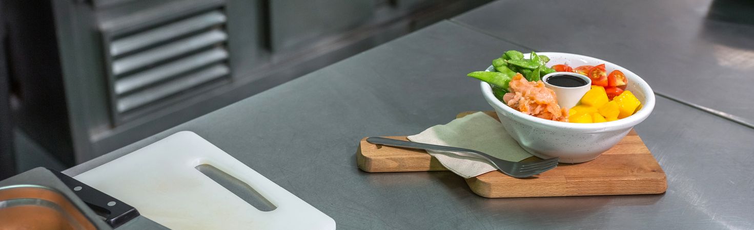 Banner of salmon poke bowl over wooden board ready on restaurant kitchen. Healthy food concept.