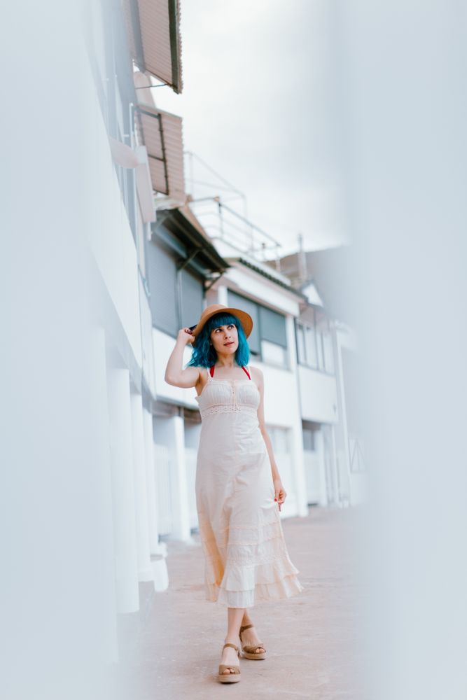 Carefree woman in sundress walking along sunny street