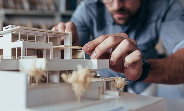 Male architect working on model in office